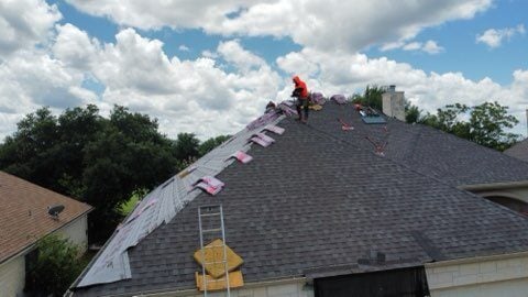 Roofers repairing storm damaged roof. 